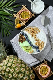 Tasty smoothie bowl with fresh kiwi fruit, blueberries and oatmeal served on black table, flat lay