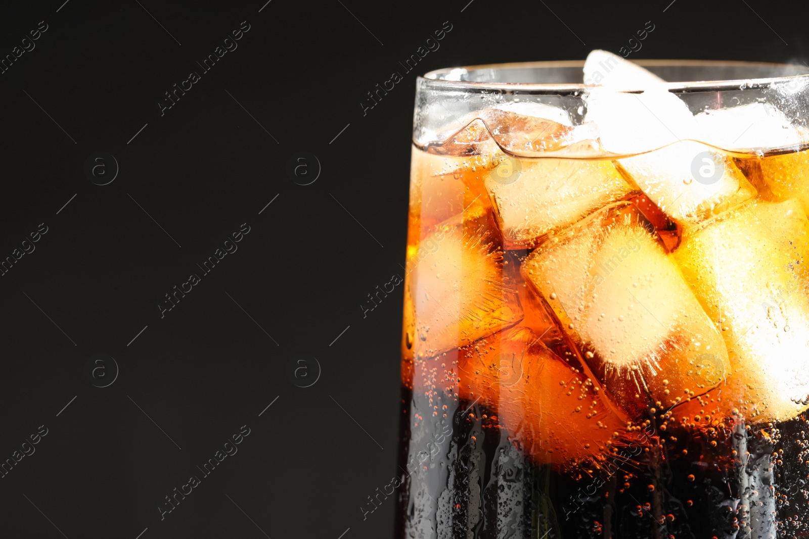 Photo of Glass of refreshing soda drink with ice cubes on black background, closeup