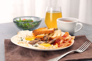 Plate with fried eggs, bacon and toasts on table