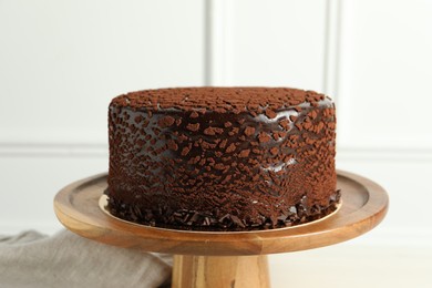 Photo of Delicious chocolate truffle cake on table near white wall