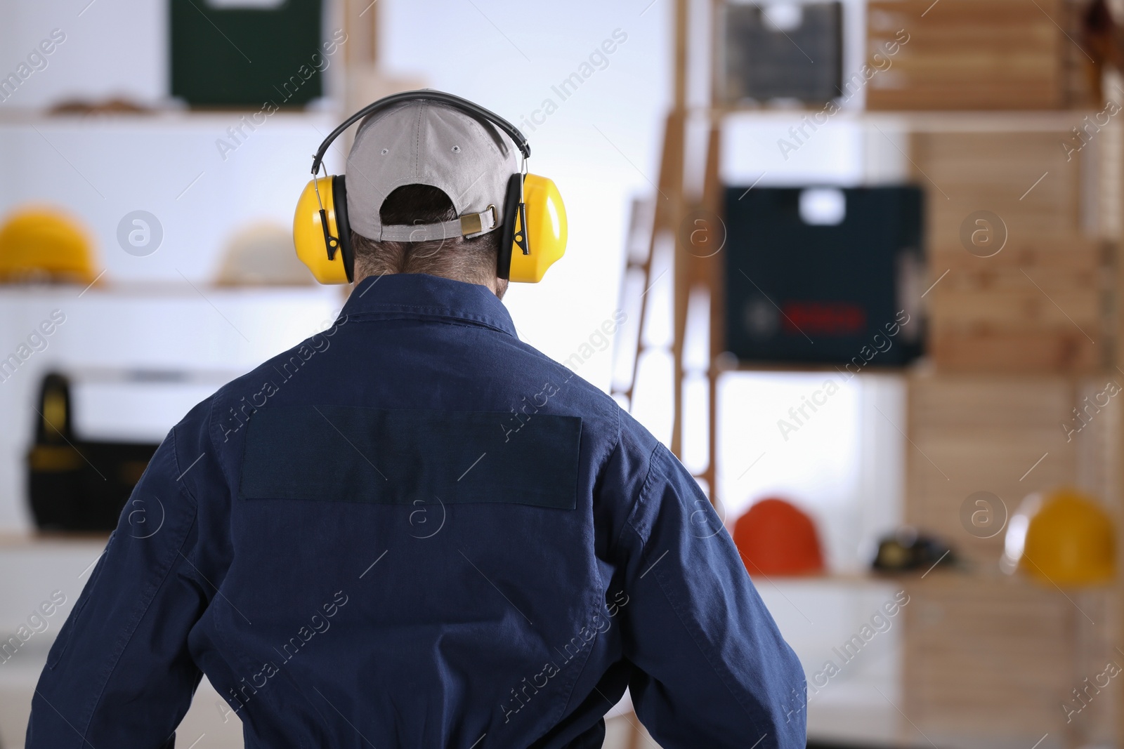 Photo of Worker wearing safety headphones indoors, back view. Hearing protection device