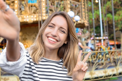 Photo of Attractive woman taking selfie in amusement park