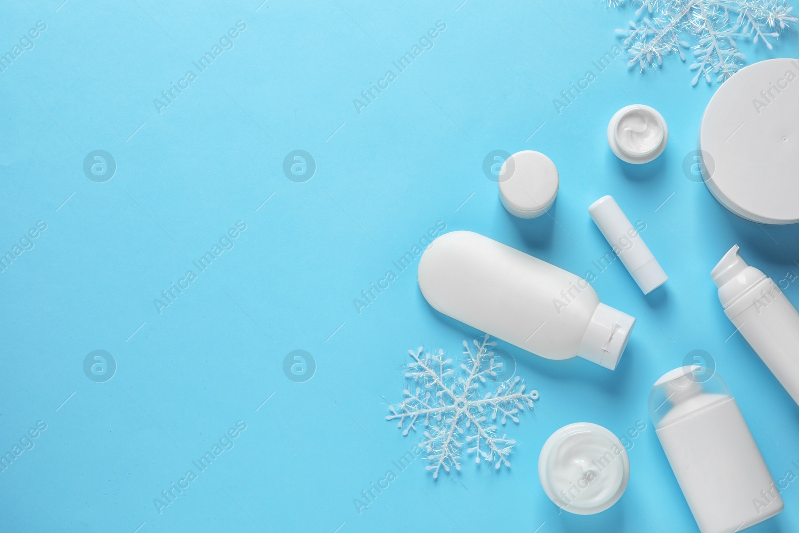 Photo of Set of cosmetic products on blue background, flat lay with space for text. Winter care