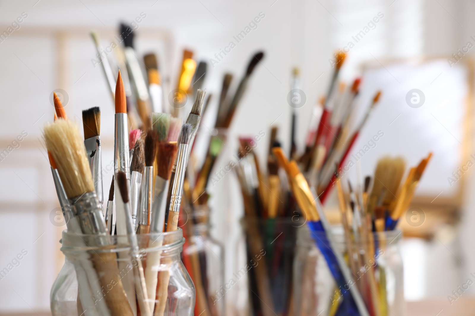 Photo of Holders with many different paintbrushes indoors, closeup