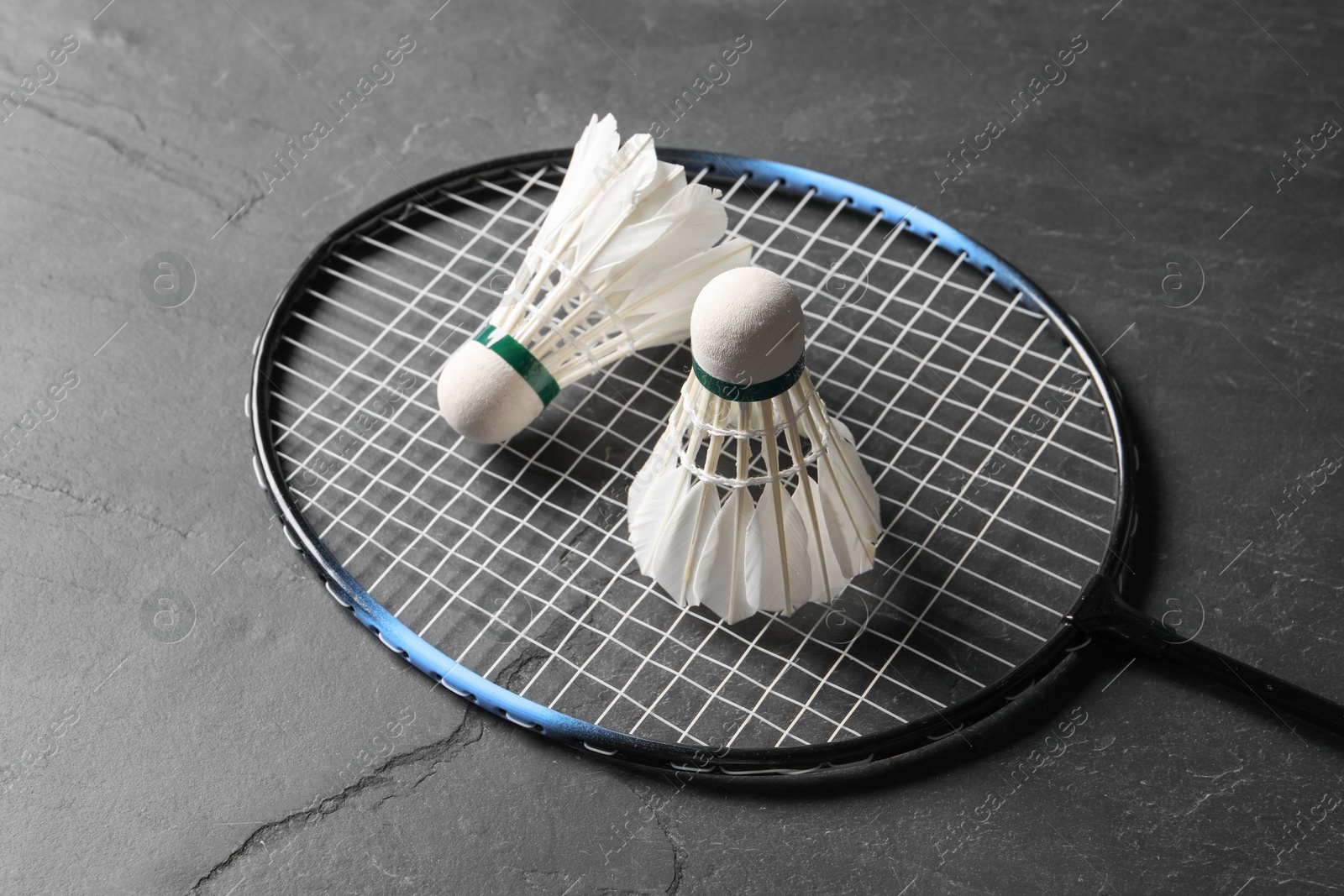 Photo of Feather badminton shuttlecocks and racket on grey textured table