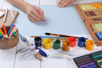 Artist drawing with chalk pastel at white wooden table, closeup