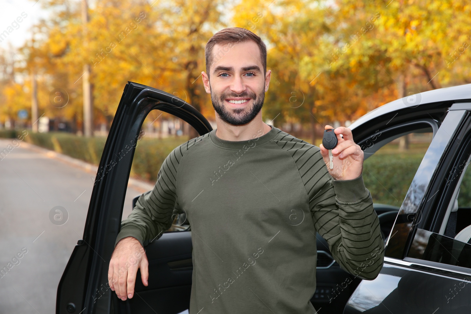 Photo of Young man holding car key near auto. Driving license test