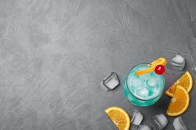 Glass of tasty refreshing cocktail on grey stone background, flat lay. Space for text