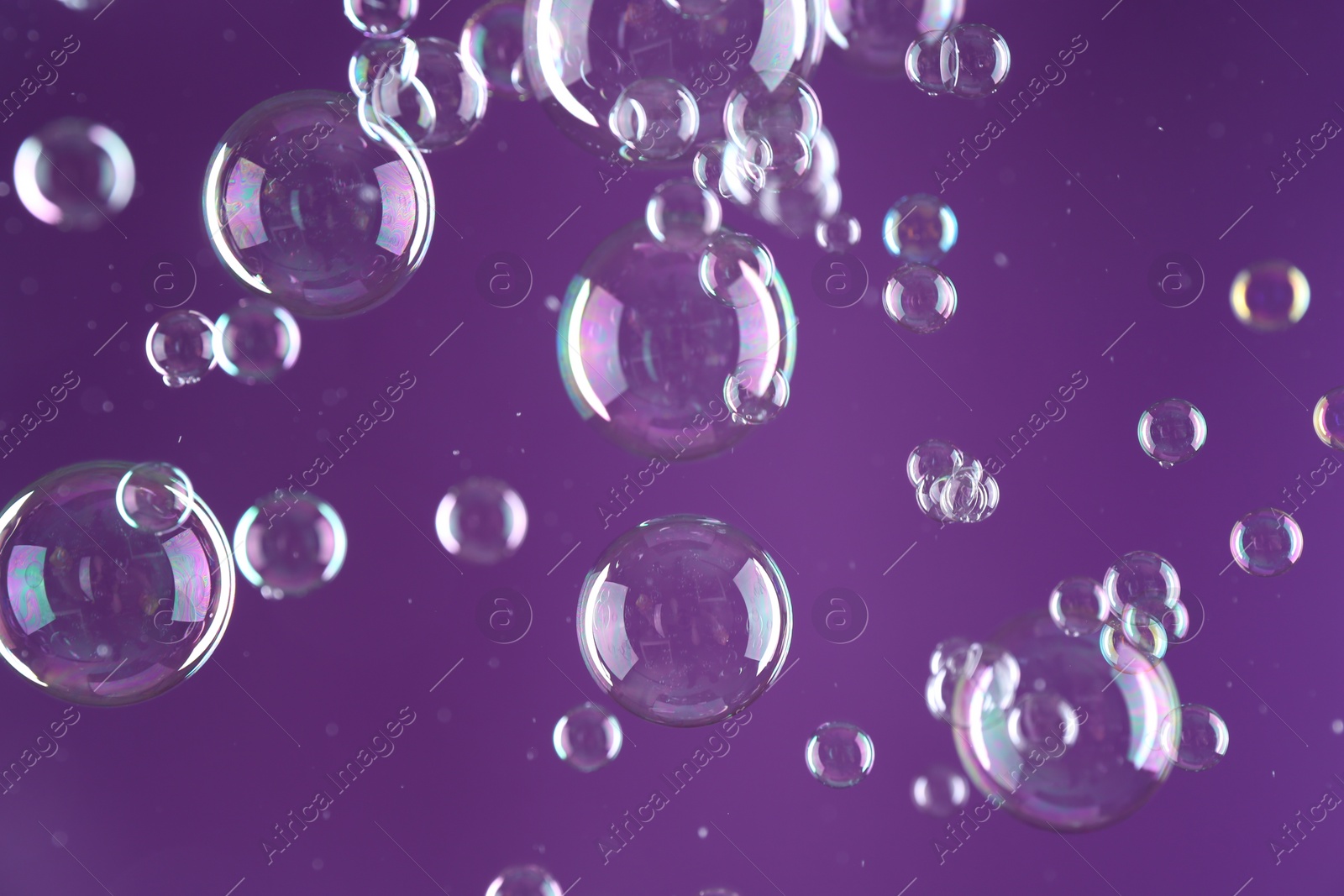 Photo of Beautiful transparent soap bubbles on purple background