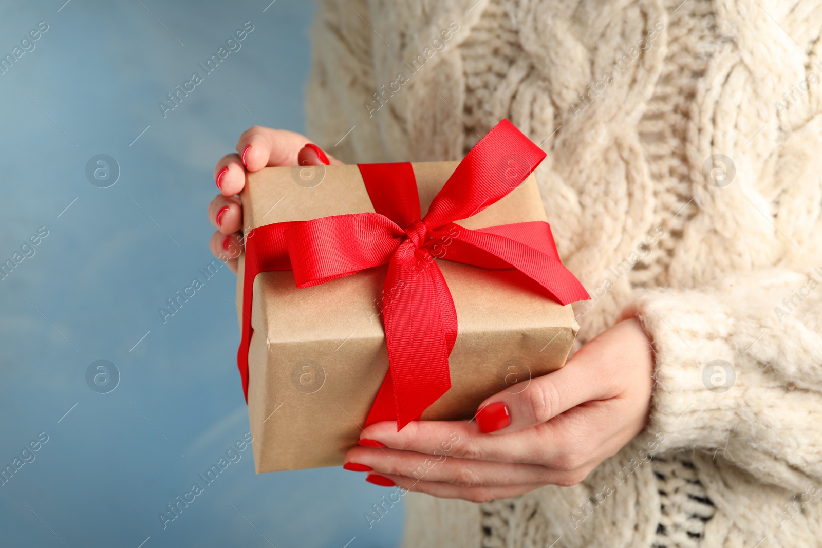 Photo of Young woman holding Christmas gift on blue background, closeup