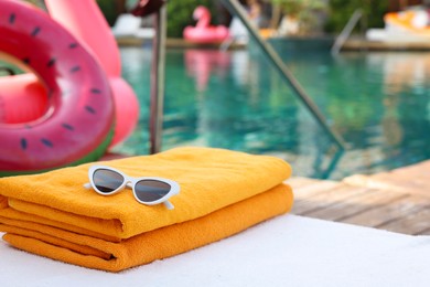 Beach towel and sunglasses on sun lounger near outdoor swimming pool. Luxury resort