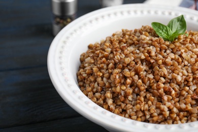 Photo of Bowl of buckwheat porridge with basil on table, closeup. Space for text