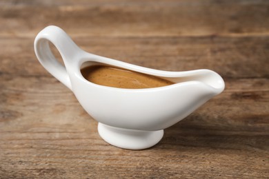 Photo of Delicious turkey gravy in sauce boat on wooden table