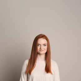 Candid portrait of happy young woman with charming smile and gorgeous red hair on beige background
