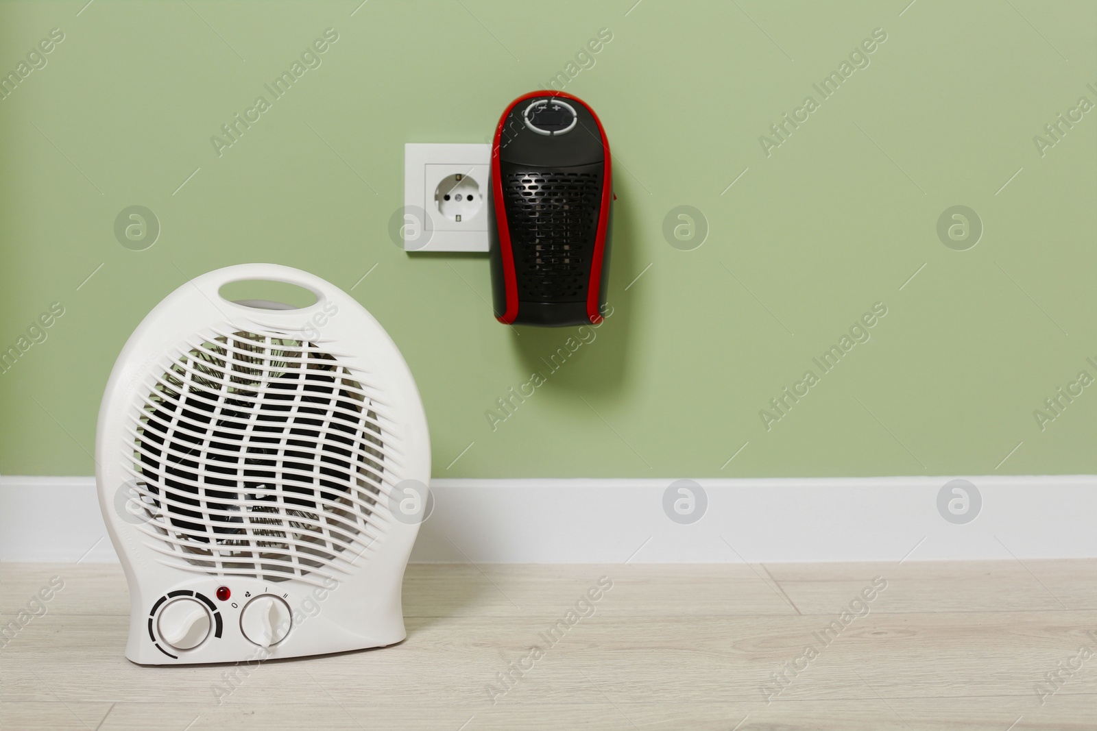Photo of Different electric heaters near pale green wall indoors. Space for text