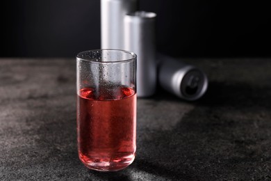 Photo of Energy drink in glass and aluminium cans on grey table. Space for text