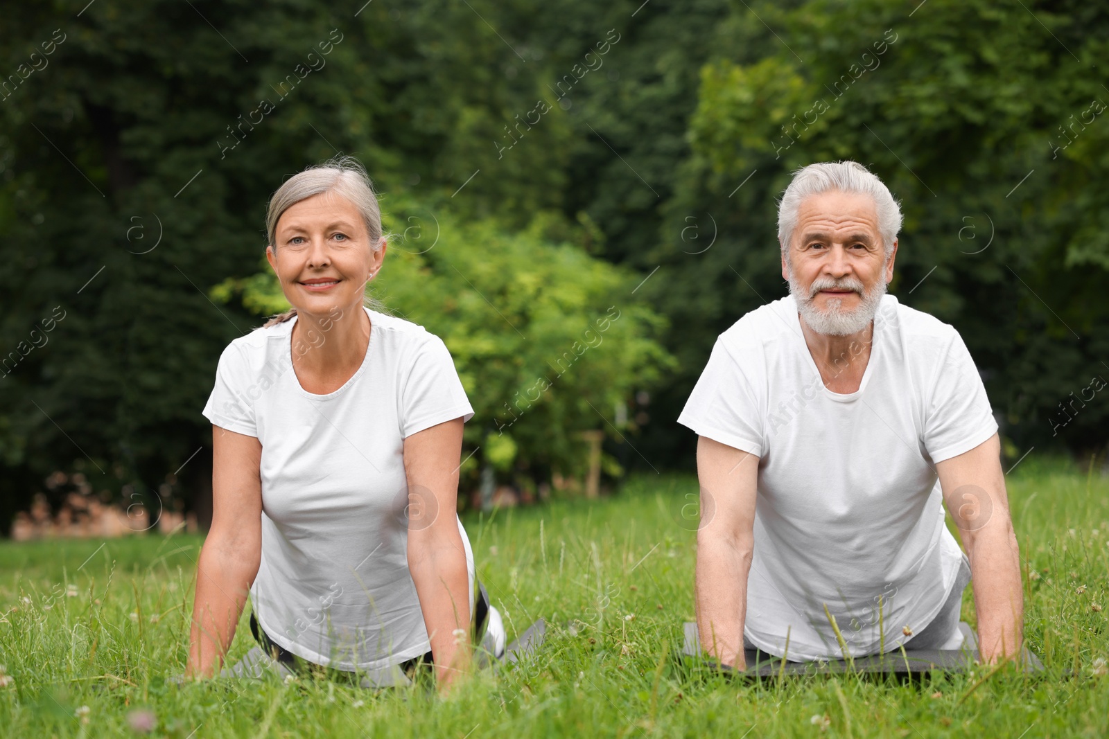 Photo of Senior couple practicing yoga on green grass in park