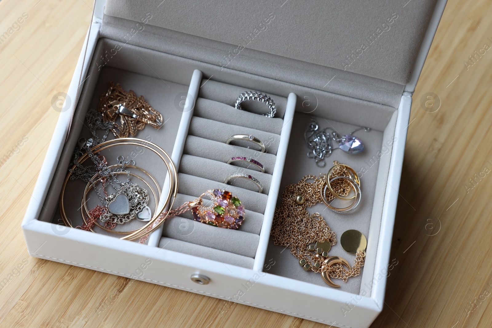 Photo of Jewelry box with many different accessories on wooden table, above view