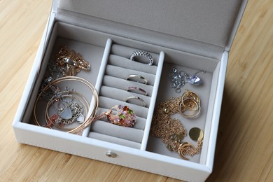 Photo of Jewelry box with many different accessories on wooden table, above view