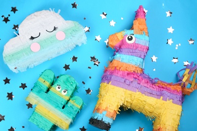 Different bright pinatas on light blue background, flat lay