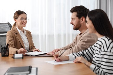 Photo of Couple signing document while having meeting with lawyer in office