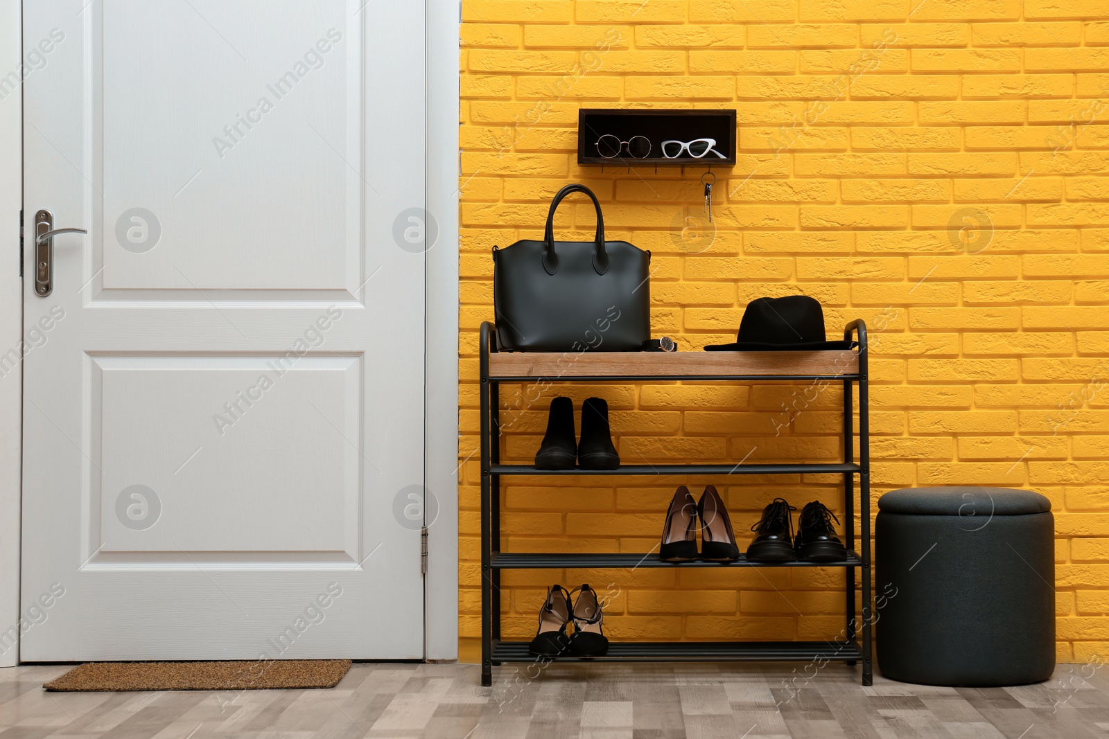 Photo of Shelving unit with shoes near yellow brick wall in hallway