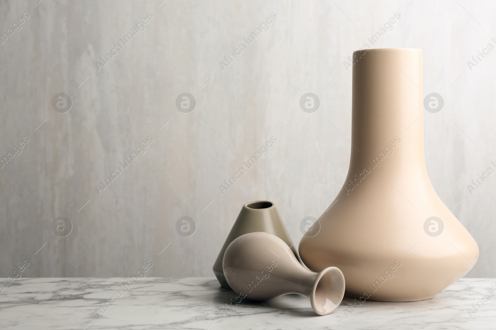 Photo of Stylish empty ceramic vases on white marble table, space for text