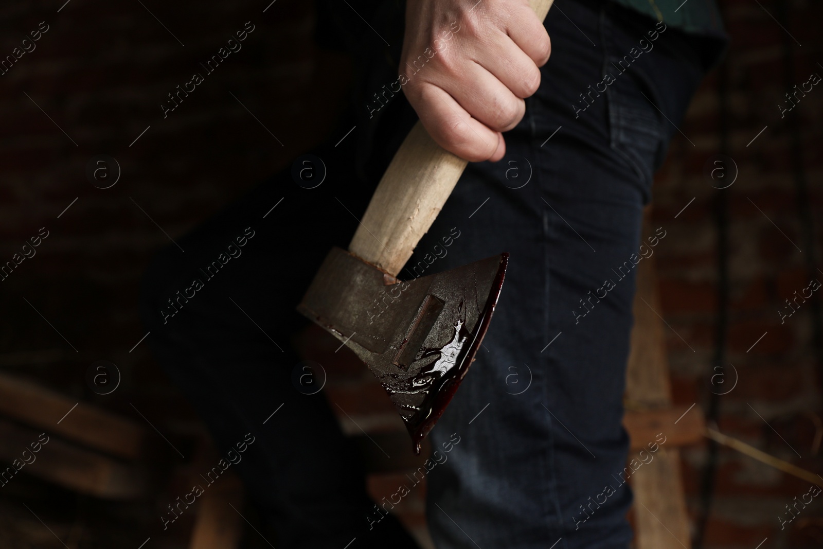 Photo of Man holding bloody axe indoors, closeup view