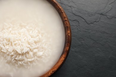 Photo of Rice soaked in water on black table, top view. Space for text