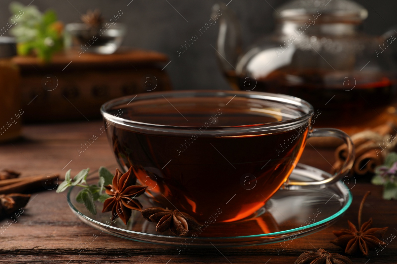 Photo of Aromatic tea with anise stars and mint on wooden table, closeup
