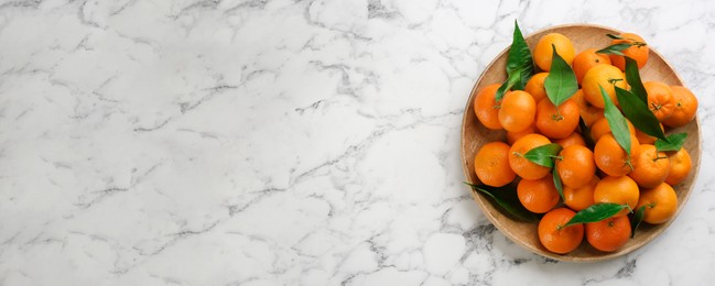 Fresh ripe tangerines and green leaves on white marble table, top view with space for text. Banner design