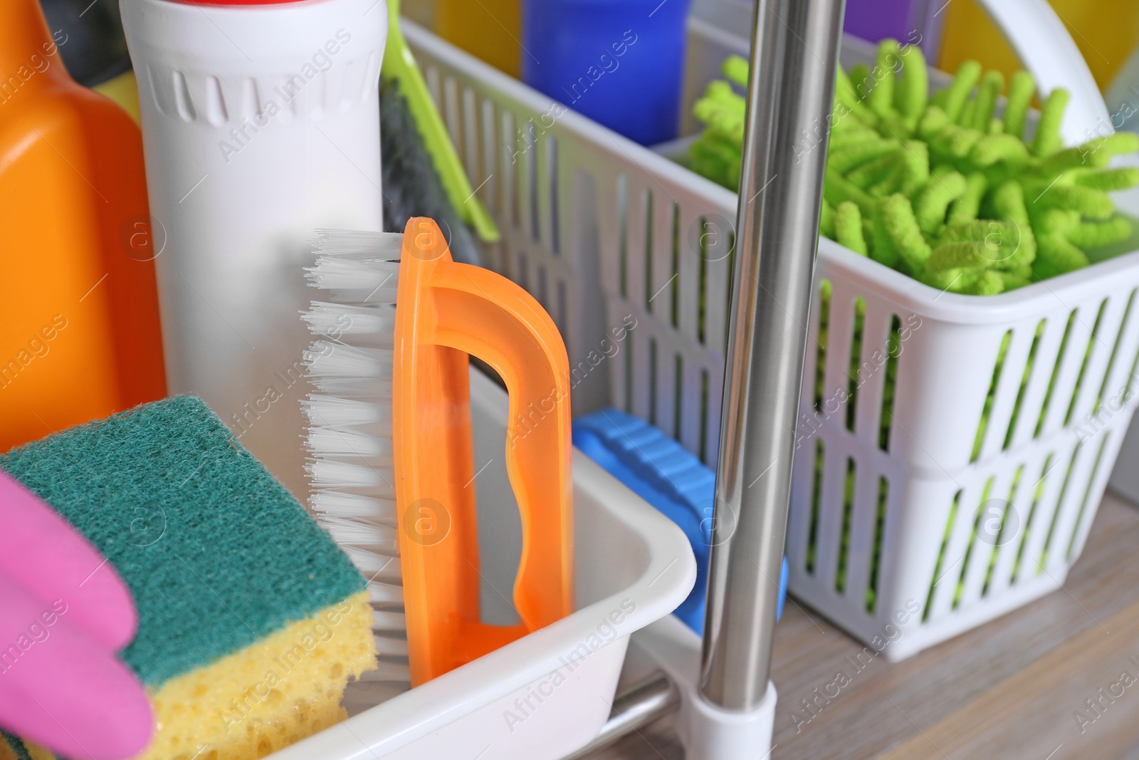 Photo of Different cleaning supplies on wooden table in kitchen, closeup