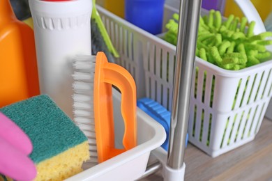 Photo of Different cleaning supplies on wooden table in kitchen, closeup