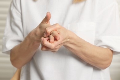 Woman cracking her knuckles on blurred background, closeup. Bad habit