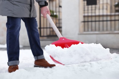 Photo of Man removing snow with shovel outdoors, closeup