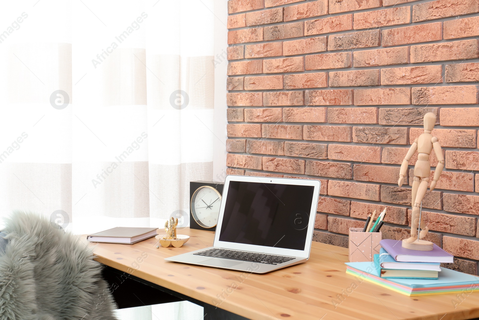 Photo of Stylish workplace interior with laptop on table near brick wall. Space for text