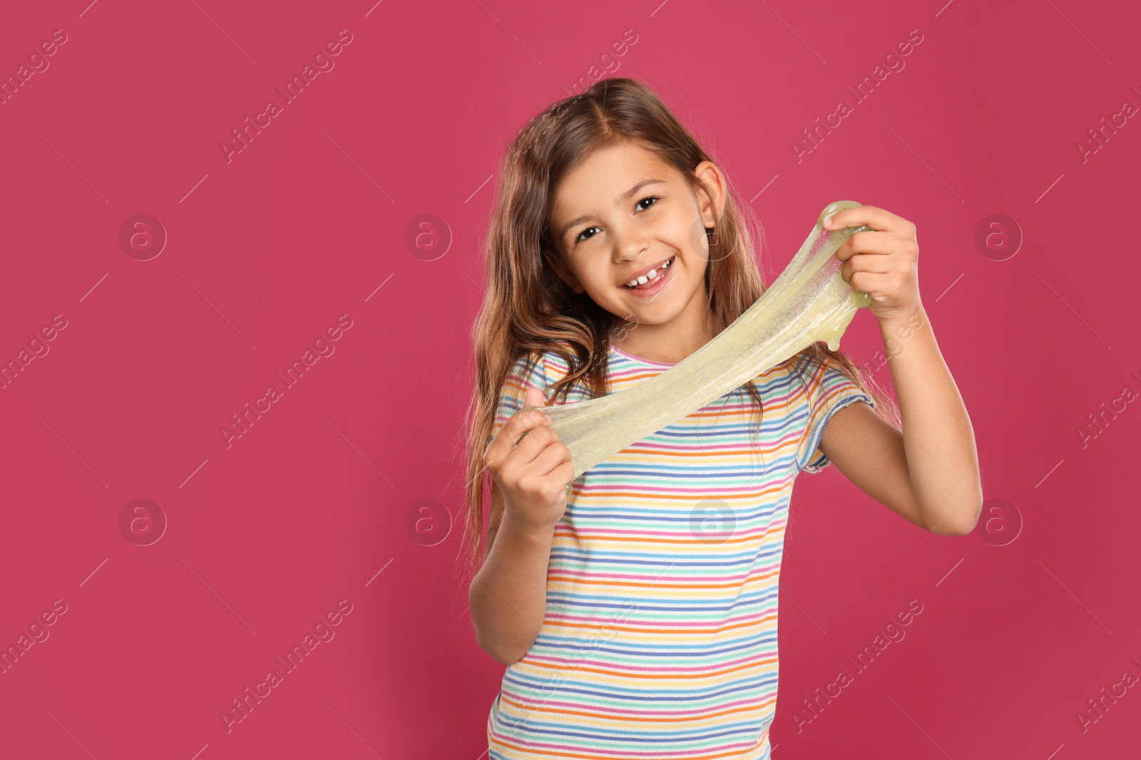 Photo of Little girl with slime on pink background