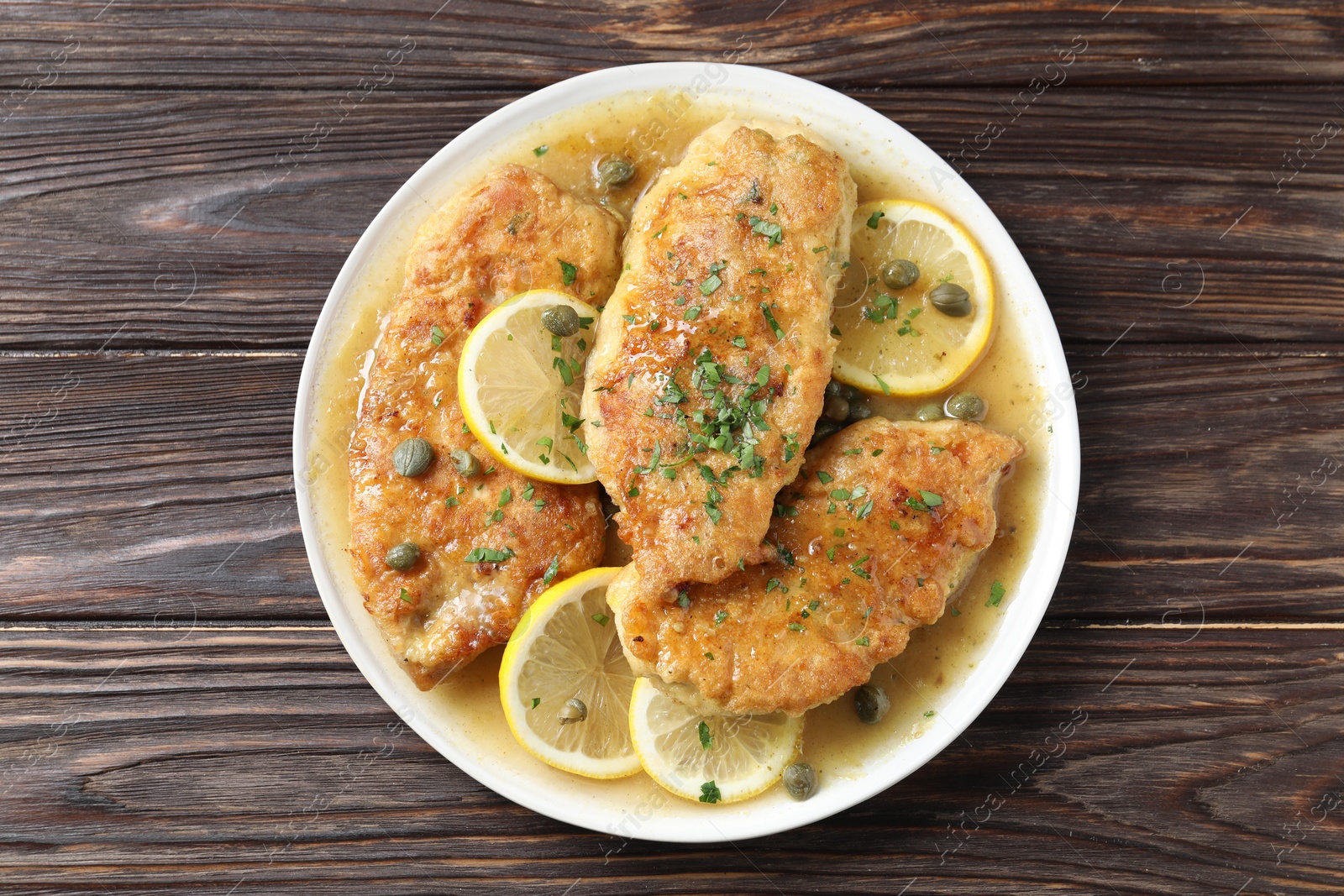 Photo of Delicious chicken piccata on wooden table, top view