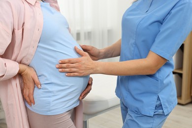 Photo of Pregnancy checkup. Doctor examining patient's tummy in clinic, closeup