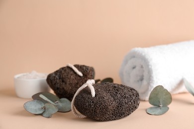 Pumice stones, eucalyptus and towel on beige background, space for text