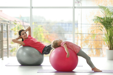 Photo of Woman and daughter doing exercise with fitness balls at home