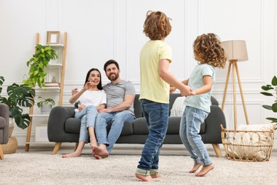 Children dancing while their parents looking at them in room