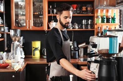 Portrait of barista using coffee grinding machine in cafe