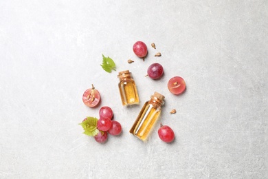 Flat lay composition with bottles of natural grape seed oil on grey table. Organic cosmetic