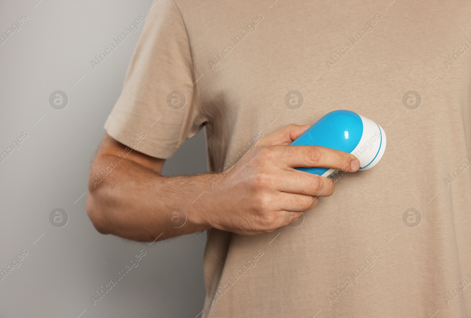 Photo of Man using fabric shaver on light grey background, closeup