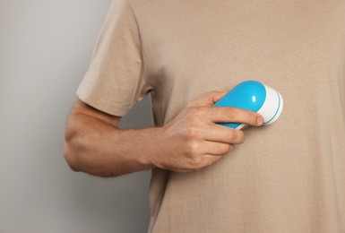 Man using fabric shaver on light grey background, closeup