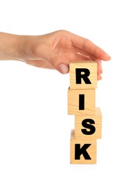 Photo of Woman stacking wooden cubes with word Risk on white background, closeup