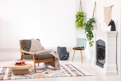 Stylish living room interior with comfortable armchair, blanket and fireplace