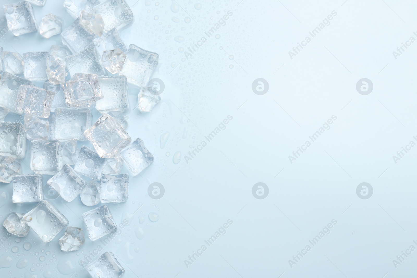 Photo of Crystal clear ice cubes on light blue background, flat lay. Space for text