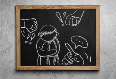 Photo of Blackboard with drawn people bullying sad human on grey background, top view